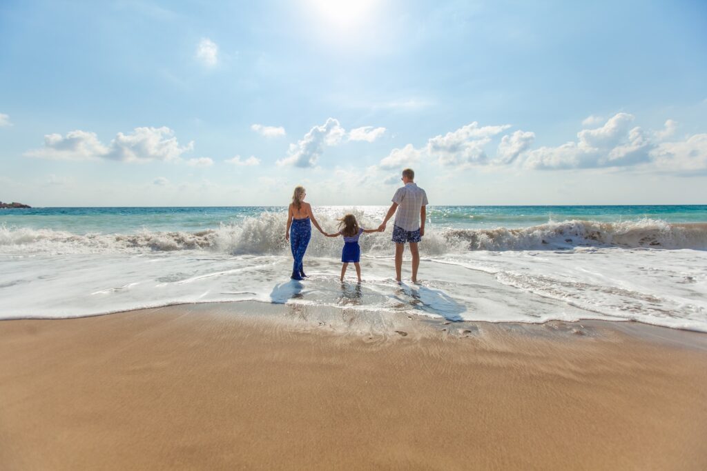 Un couple et leur petite fille à la plage face à la mer
