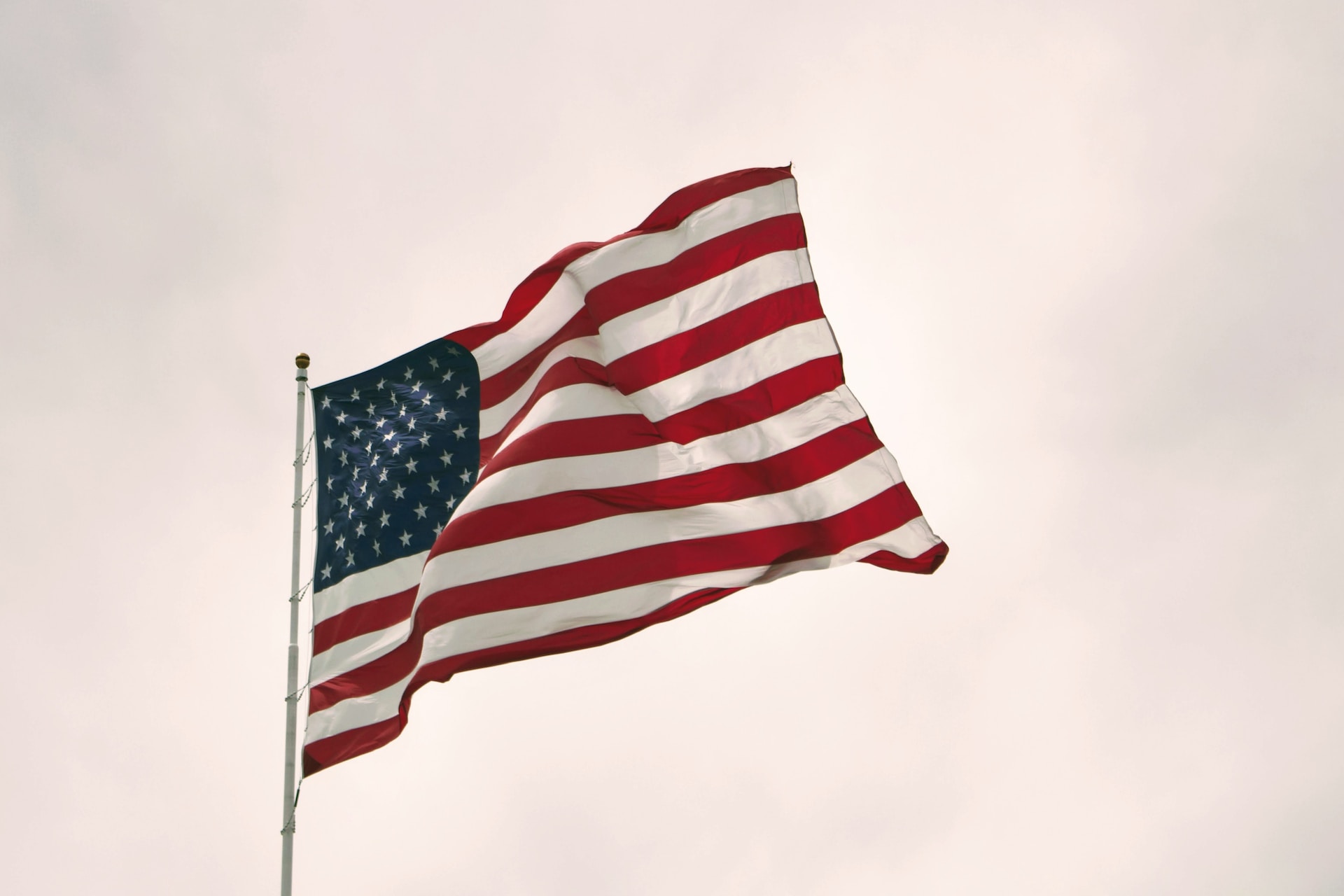 Un drapeau américain flotte dans un ciel gris.