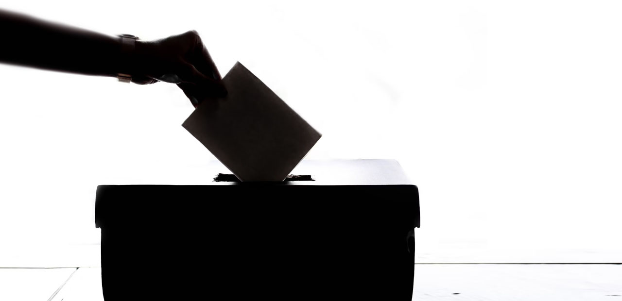 Bulletin de vote glissé dans une urne en contre-jour
